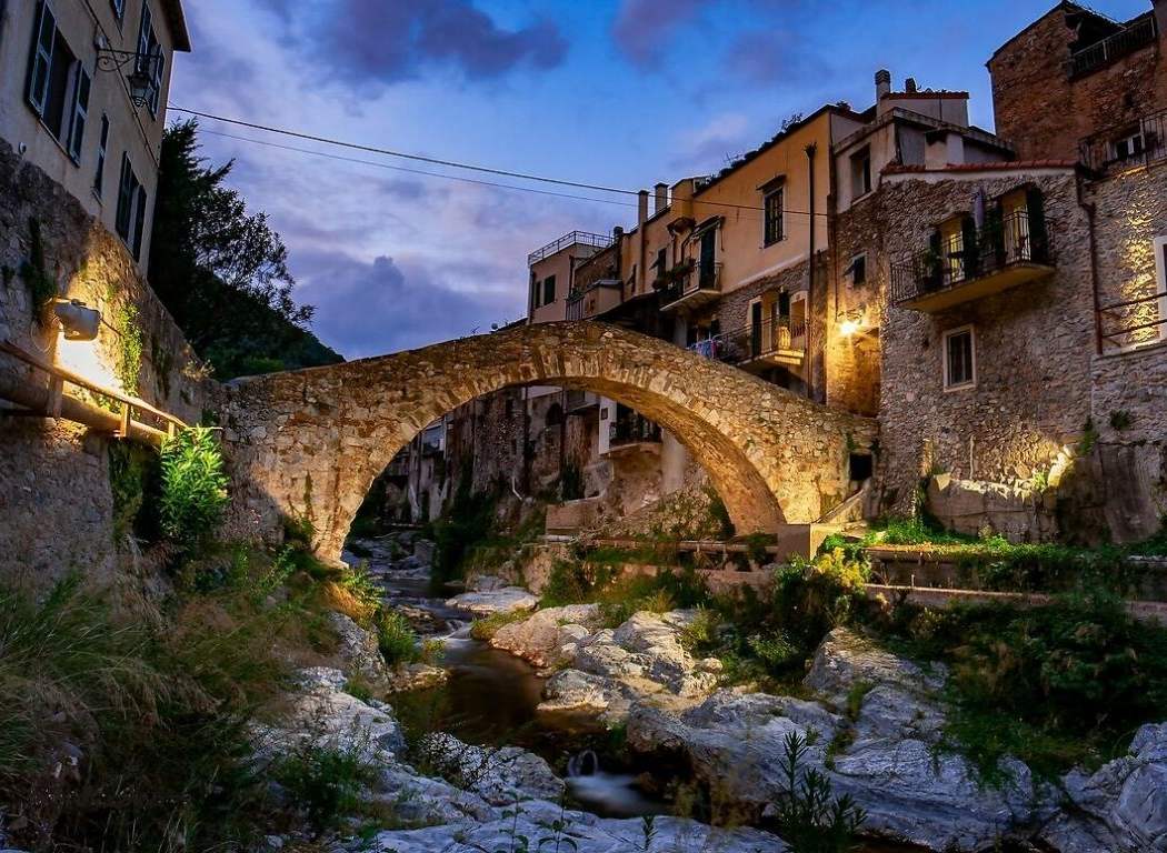 Un antico ponte romano su un fiume con vecchie case ai lati